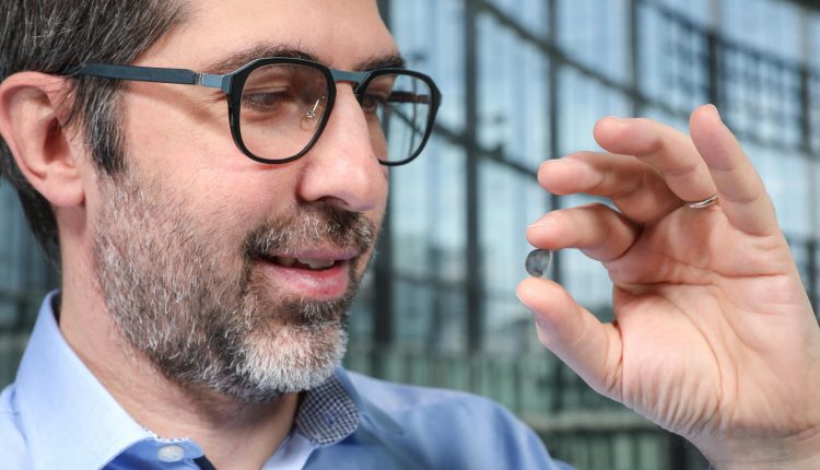 The researcher Diego Ghezzi holds a contact lens with photovoltaic points on it.